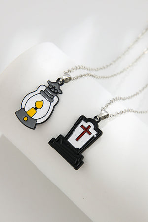 Spooky Season enamel pendant necklaces, one a lantern with yellow flame, one a tombstone with red cross.