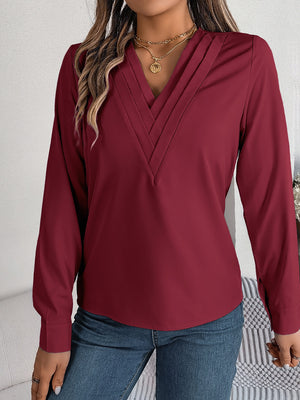 Burgundy V-neck blouse with pleated neckline and long sleeves.