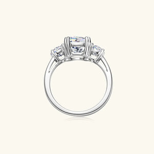 Silver three-stone cushion cut moissanite ring with a solitaire center stone and two smaller side stones.