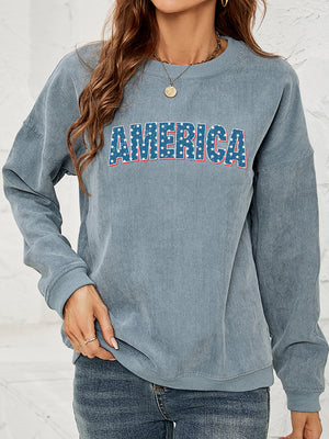 French Blue corduroy sweatshirt with "AMERICA" graphic in stars and stripes pattern.