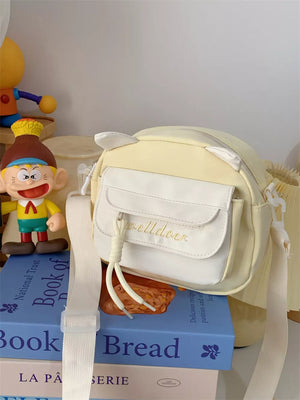 Yellow crossbody bag with cat ears and white pocket detail.