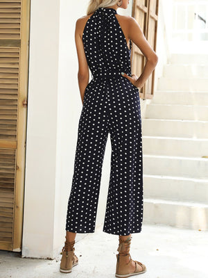 Navy polka dot wide-leg romper with halter neck and belted waist.