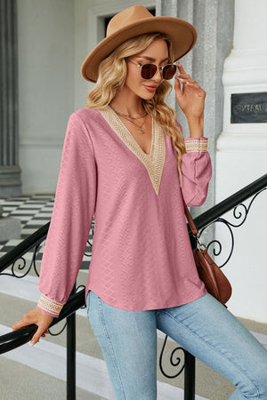 Pink textured V-neck blouse with embroidered trim on neckline and cuffs.