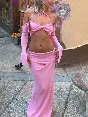 Pink halter neck two-piece knit set with twisted front crop top and long sleeves, and a maxi skirt.