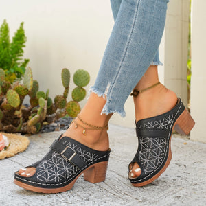 Black block heel sandals with buckle detail and white floral embroidery.