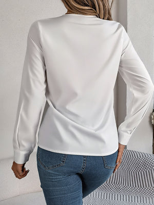 White long sleeve blouse with V-neckline and button cuffs.