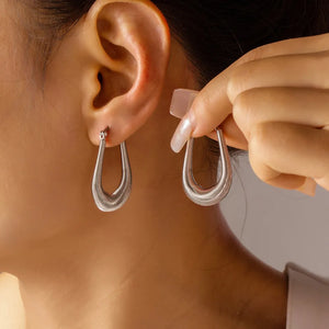 Silver coiled oval hoop earrings with a textured finish.