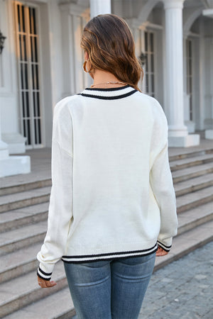 White acrylic knit cardigan with contrast black trim on neckline and hem