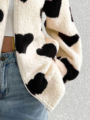 Heart print sherpa zip-up jacket in cream with black hearts, featuring a fuzzy texture.