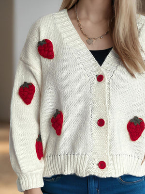 Cream knit cardigan with red strawberry appliqués and red buttons.