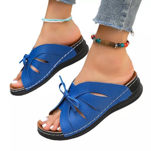 Blue criss-cross wedge sandals with bow detail and white stitching.