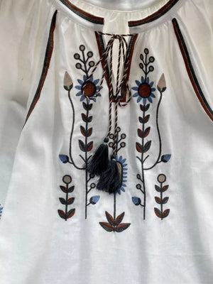 White tie neck blouse with colorful floral embroidery and tassels