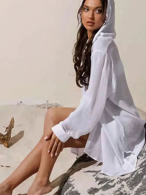 White oversized linen hooded shirt dress with button details and long sleeves.