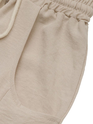 Tan palazzo trousers with drawstring waist and pockets, made from breathable fabric.
