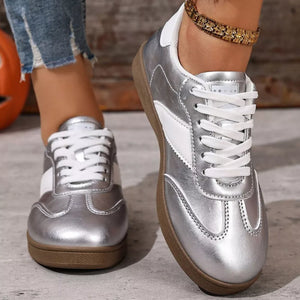 Silver patent leather lace-up sneakers with white accents and brown soles.