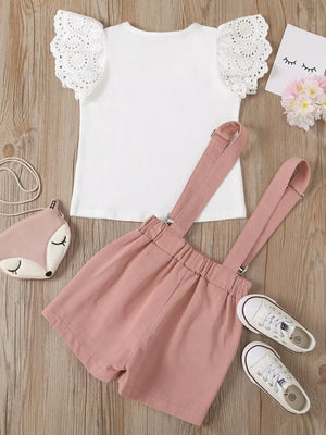 Baby girl outfit with white eyelet lace sleeve top and pink suspender shorts.