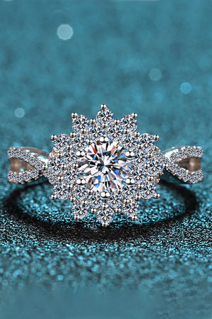 Silver ring with a large round center moissanite surrounded by a halo of smaller stones in a floral design.