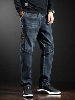 Men's dark wash loose fit drawstring jeans with distressed details and side text