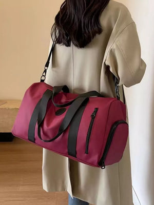 Wine red travel bag with adjustable straps and zippered pockets, worn crossbody.
