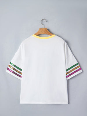 White cotton t-shirt with yellow neckline and sequin striped sleeves in green, gold, and purple.