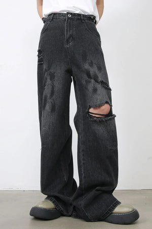 Rugged relaxed fit dark wash denim jeans with distressed rips and wide leg.