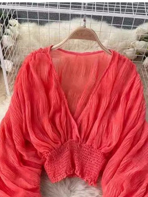 Orange ruched sleeve blouse with deep V-neck and smocked waist.