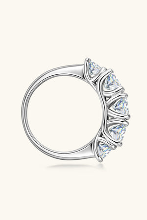 Silver five-stone moissanite eternity band ring with prong-set triangle-cut stones.