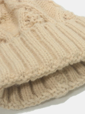 Beige cable knit acrylic beanie with ribbed cuff detail.