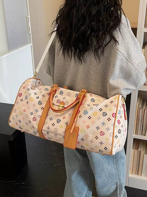 Vibrant monogram leather travel bag with adjustable strap and tan trim.