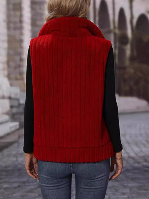 Plush corduroy zip-up gilet in rust with a stand-up collar and vertical ribbed texture.