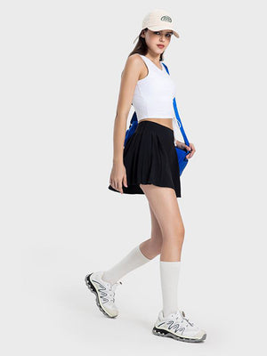 Black pleated performance mini skirt with a drawstring waist, shown on a model.