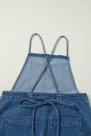 Denim wide-leg overalls in medium wash with adjustable straps and drawstring waist.