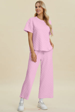 Pink textured knit loungewear set with wide leg pants and short sleeve top.