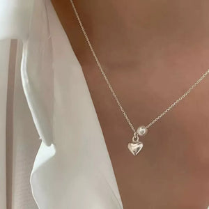 Delicate silver heart pendant necklace with pearl accent on a fine chain.