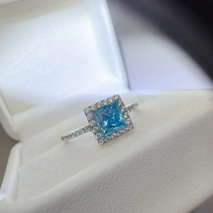 Silver ring with ice blue square halo diamond accent.