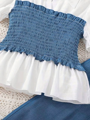 Blue smocked blouse with white ruffled peplum, paired with denim pants.