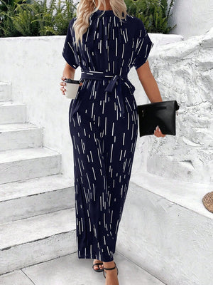 Dark blue wide-leg jumpsuit with white raindrop print, tie waist, and short sleeves.
