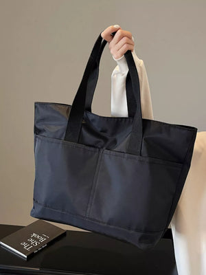Spacious black Oxford cloth shoulder tote bag with two front pockets and black straps.