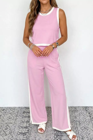 Chic colorblock two-piece set in blush pink with white trim, featuring a sleeveless crop top and wide-leg pants.