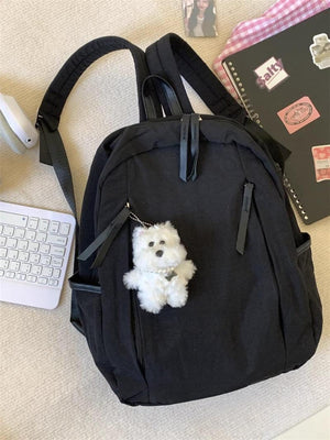 Black lightweight nylon backpack with fluffy white dog charm and pearl collar detail.