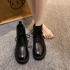 Black glossy leather combat booties with laces and side zip detail.