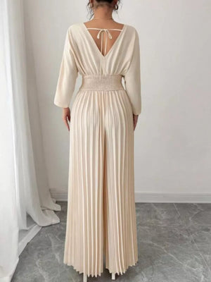 Beige pleated wide-leg jumpsuit with cinched waist and V-neck tie back.