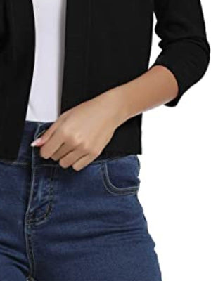 Black cropped knit cardigan with elbow sleeves and open front, styled with jeans.