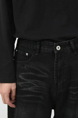 Faded black denim baggy trousers with a button fly and silver hardware.