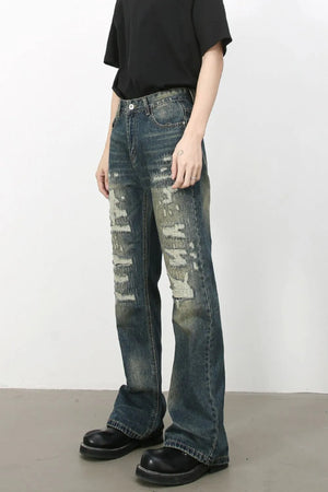 Distressed flare jeans in medium wash denim with graffiti-style rips and a comfortable cotton blend.