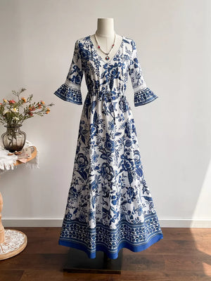 Maxi dress with blue floral print, V-neck, drawstring waist, and lace-trimmed bell sleeves.