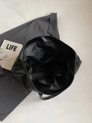 Black tote bag with open top and interior pockets, styled with a blazer.