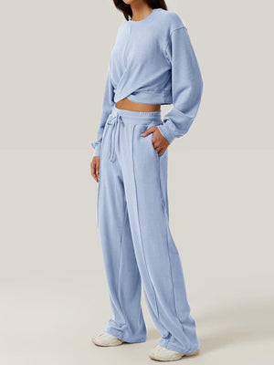 Light blue knit lounge set with a cross-front crop top and wide-leg drawstring pants.