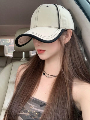 Cream white cotton baseball cap with contrast black stitching and brim detail.
