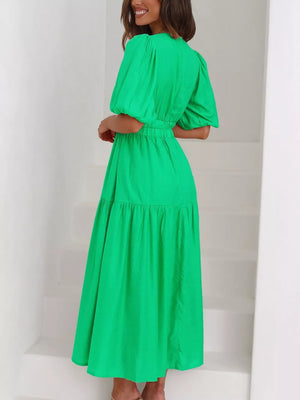 Green midi dress with puff sleeves, cinched waist, and tiered skirt.